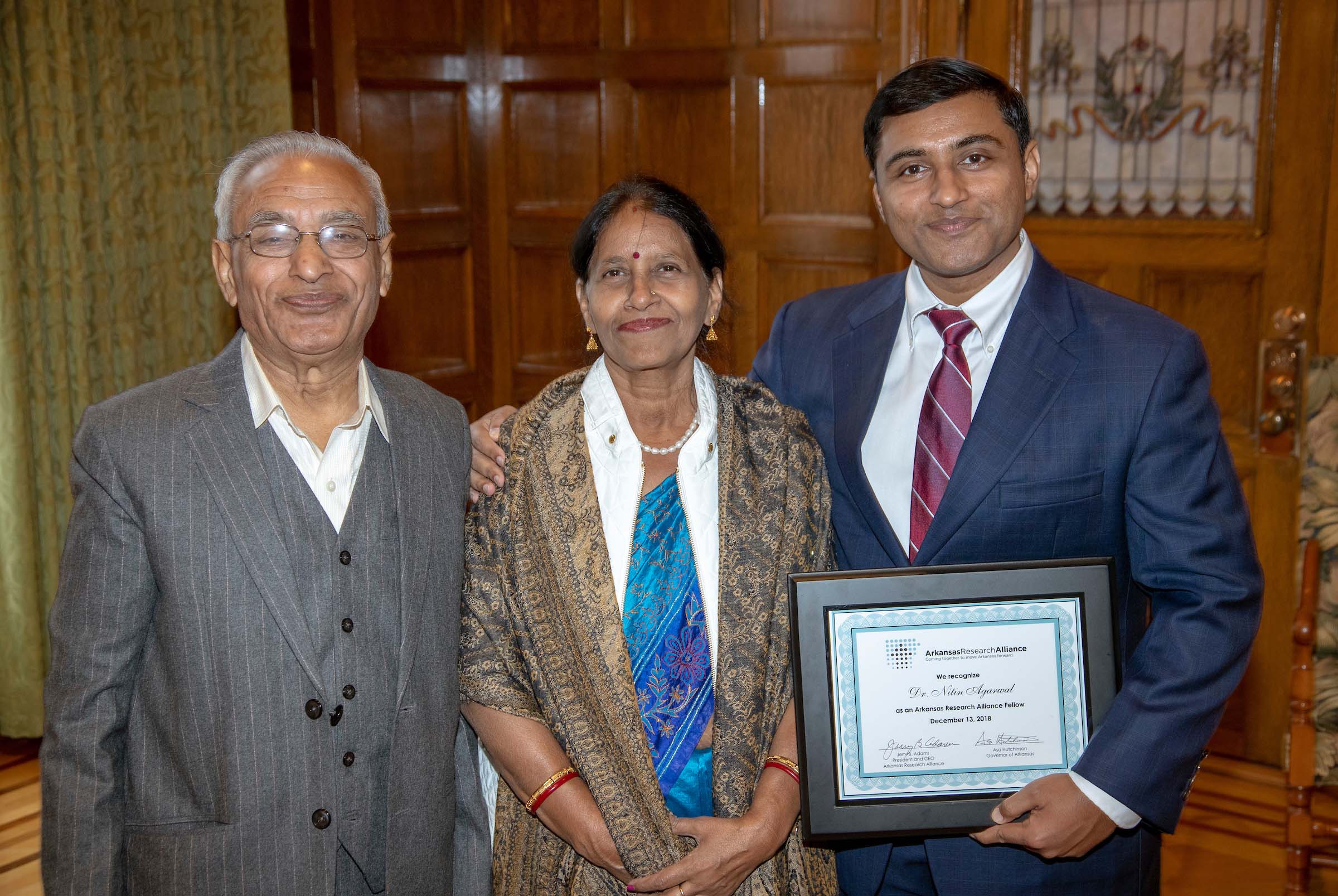 2. Dr. Nitin Agarwal celebrates with his parents as he is named a fellow of the Arkansas Research Alliance (ARA) Academy in 2018 at the Arkansas State Capitol.